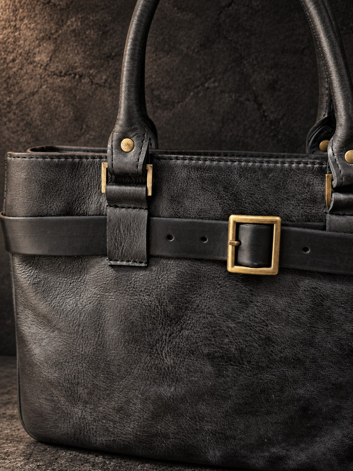 Close-up of removable black leather belt and brass buckle on hand-dyed leather handbag