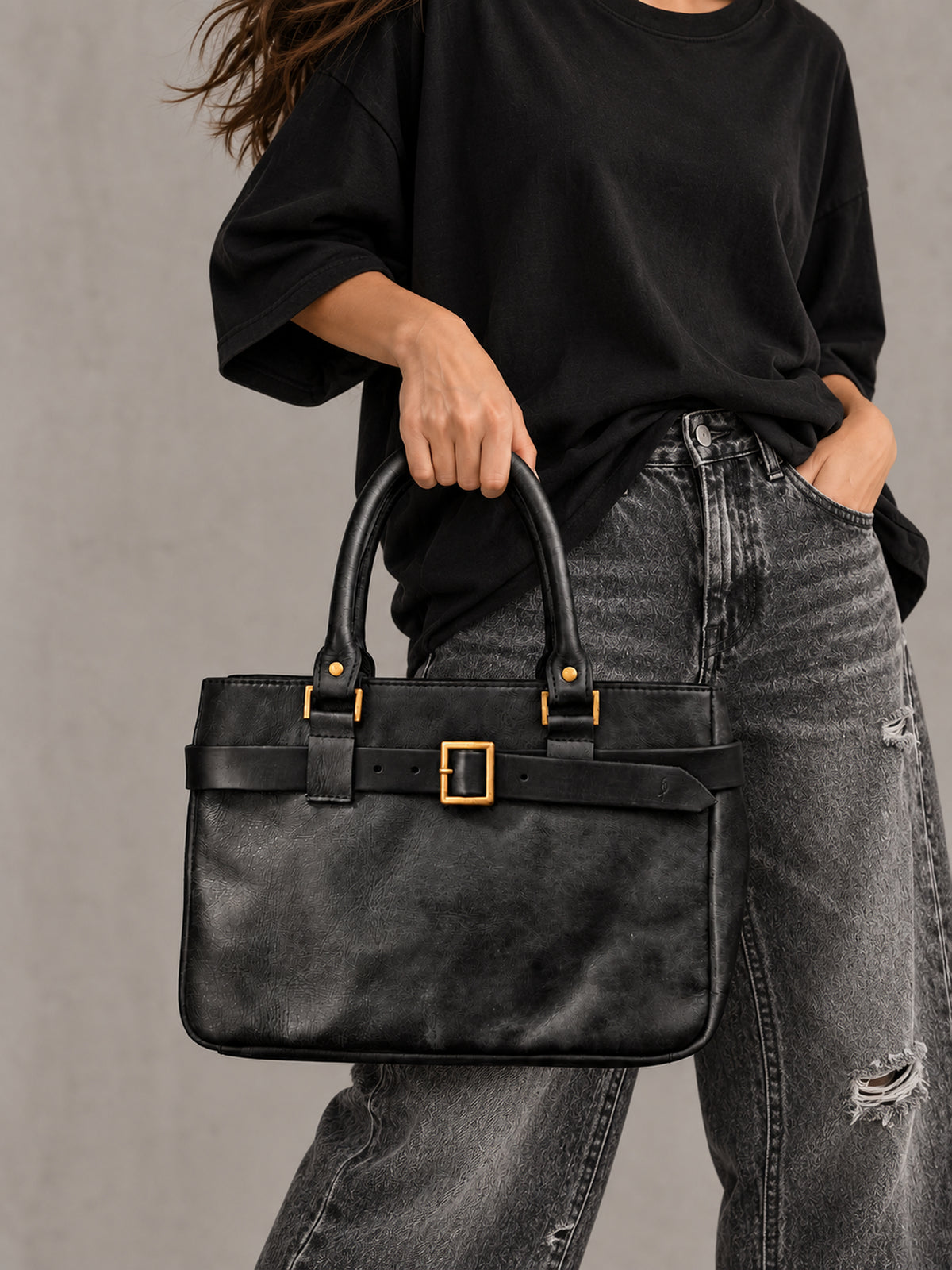 Woman carrying small black leather handbag by the top handles – handmade everyday bag