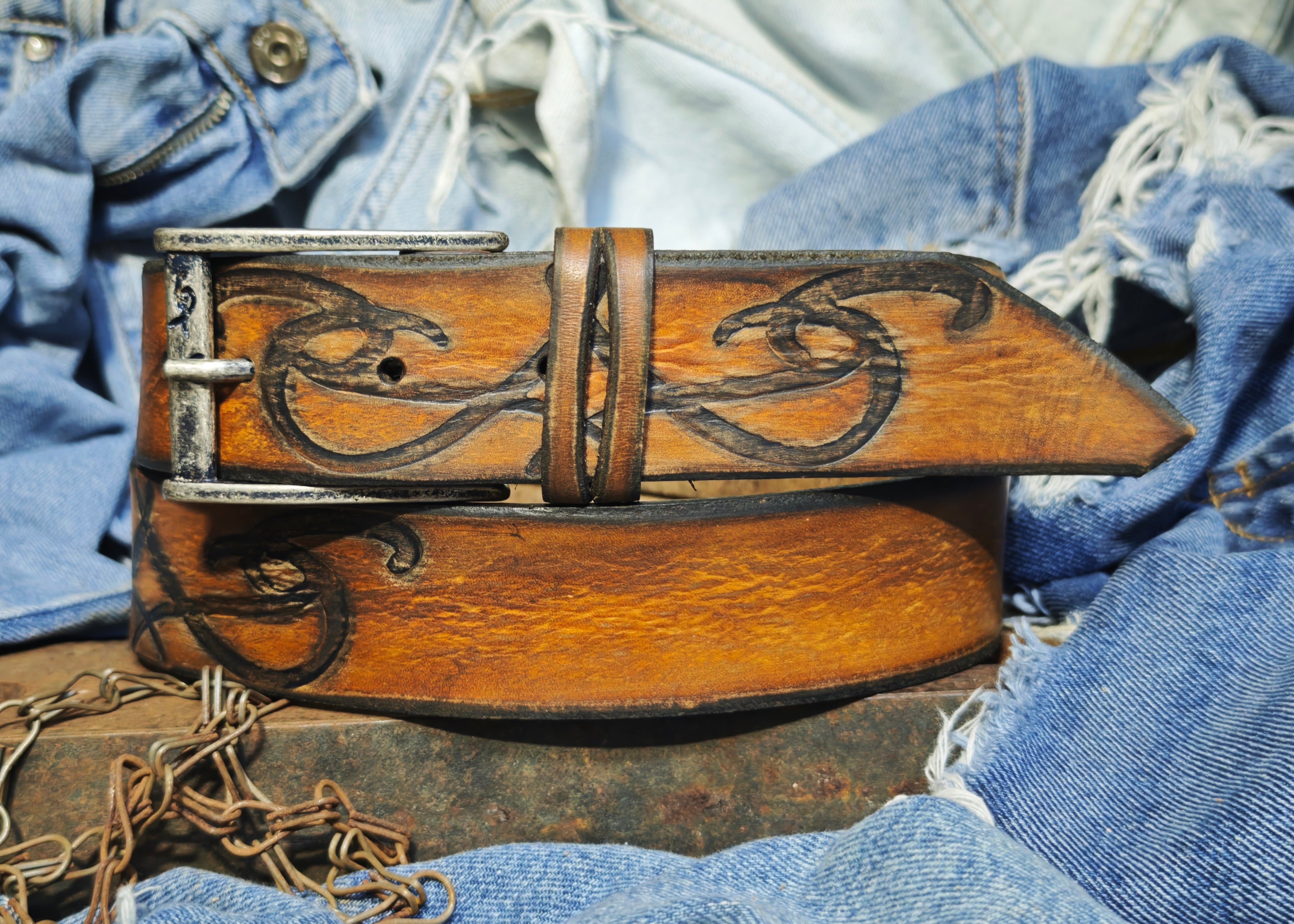Brown leather belt with a metal buckle embossed with a unique decorative pattern