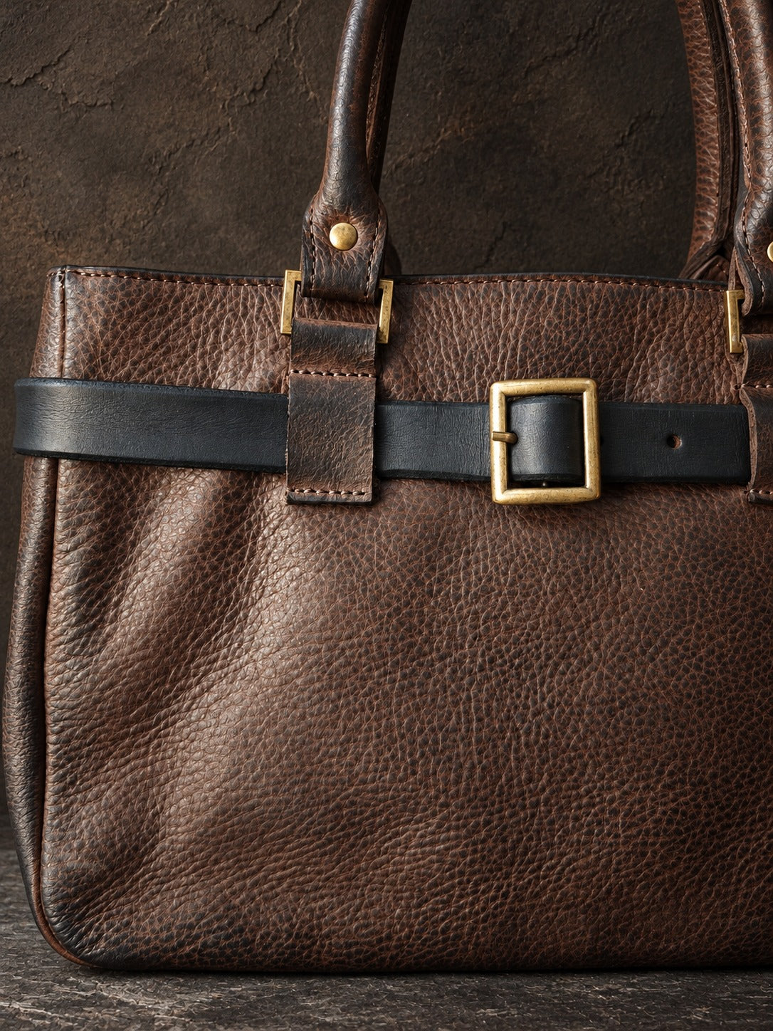 Close-up of the square brass buckle and hand-dyed dark brown leather texture
