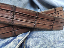 Brown leather belt with handmade cuts in the shape and texture of a crocodile
