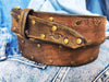 Brown leather belt with two shades of brown two pieces on the front and storage for guitar pick with bronze studs around the belt